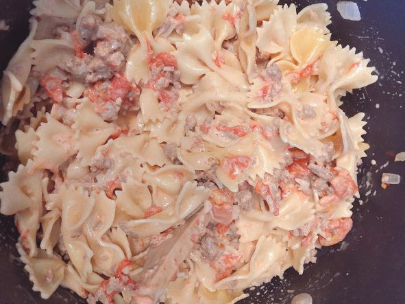 Creamy italian sausage and tomato sauce mixed with bowtie pasta in pot
