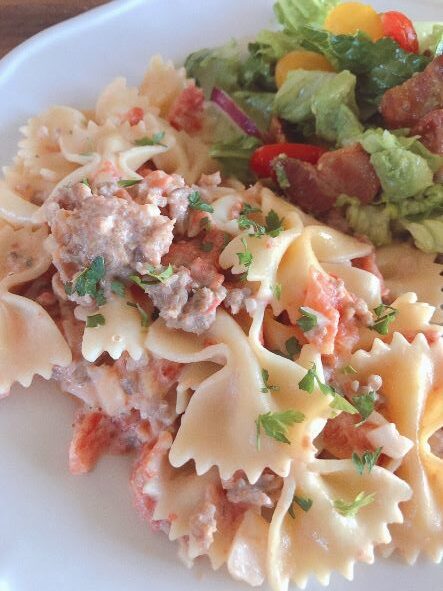 Bowtie pasta with tomatoes on plate with bacon avocado salad