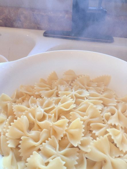 Steaming bowtie pasta drained in a white colander