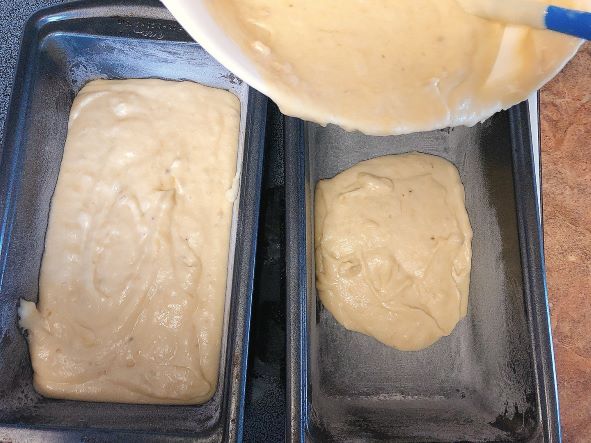pouring banana bread batter into prepared loaf pans