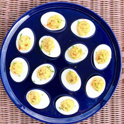 a dozen deviled eggs on a blue serving dish on wicker table