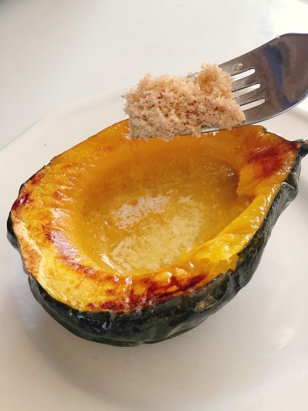 roasted acorn squash halve with butter and brown sugar on fork