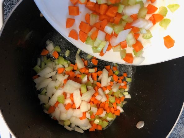 adding carrots, onion, and celery to melted butter in pot