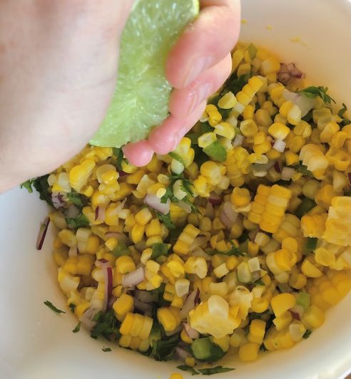 squeezing lime juice into corn salsa
