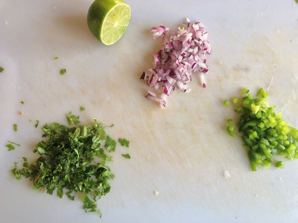 lime red onion pepper cilantro on cutting board making fresh salsa