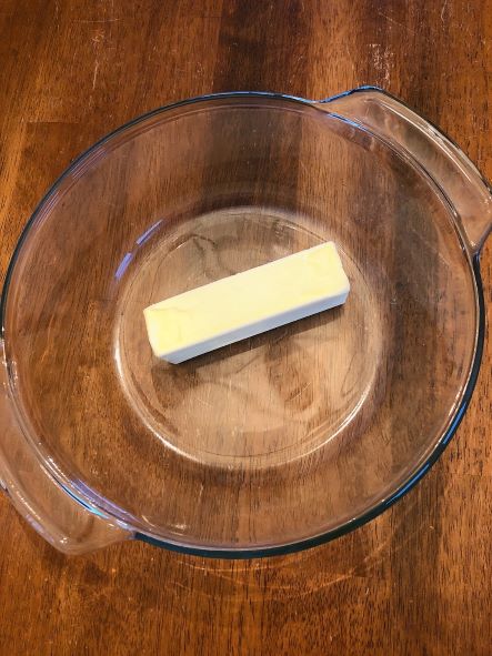 stick of butter in glass bowl on wood table