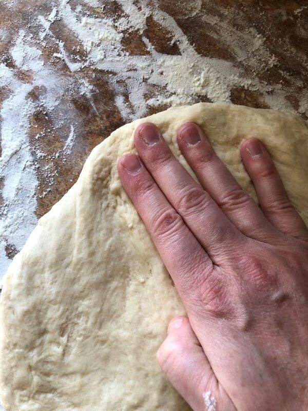using fingers to shape cinnamon roll dough into rectangle