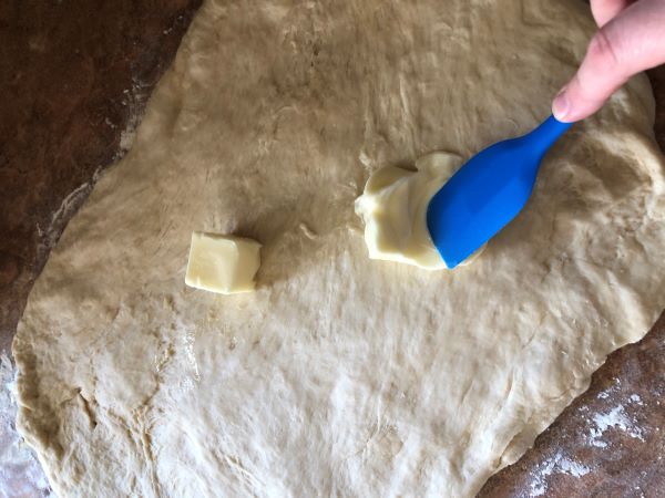 spreading butter onto dough with spatula
