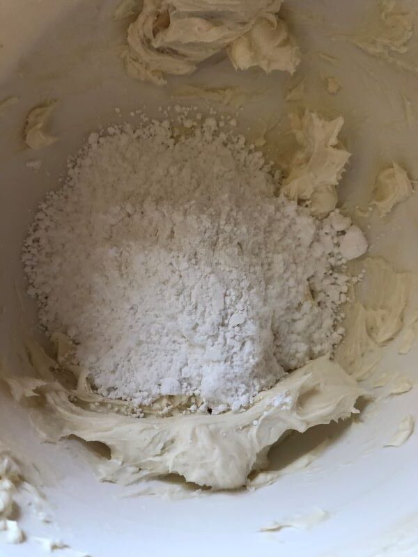 adding powdered sugar to cream cheese mixture for cream cheese frosting