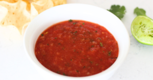 Copycat Chili's Salsa Recipe - fresh Chili's inspired salsa in white bowl with scooping, lime and tortilla chips