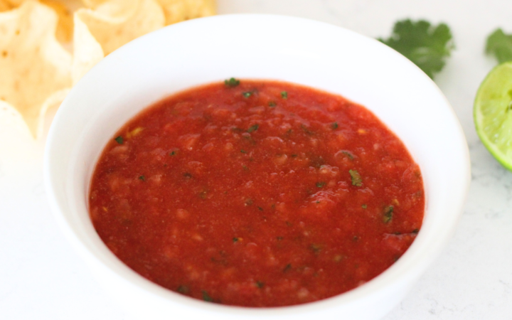 Copycat Chili's Salsa Recipe - fresh Chili's inspired salsa in white bowl with scooping, lime and tortilla chips
