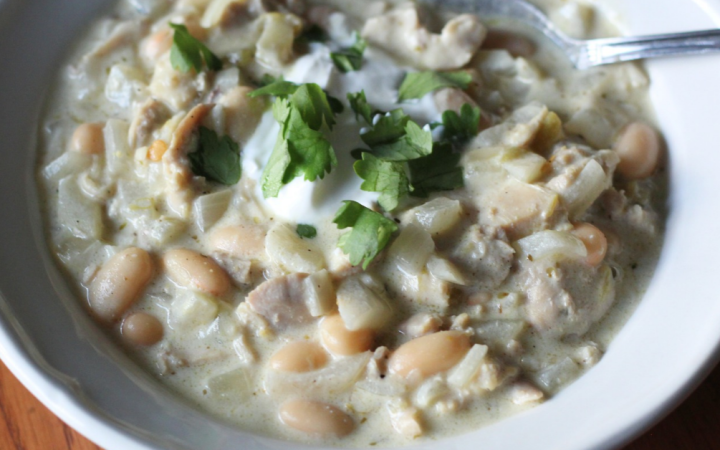 white chicken chili in a bowl topped with sour cream and fresh cilantro