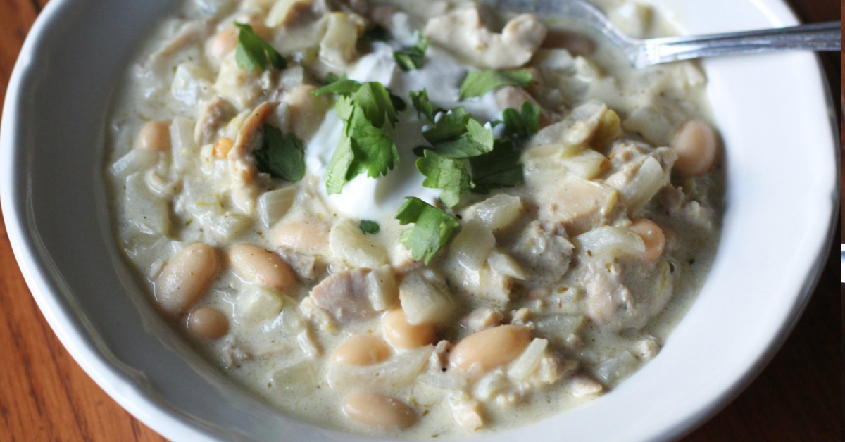 white chicken chili in a bowl topped with sour cream and fresh cilantro